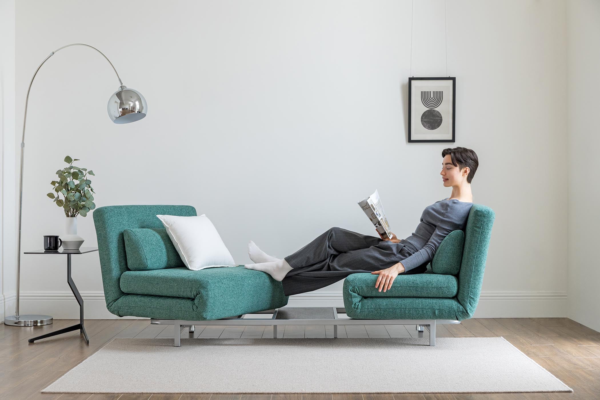 model sitting on the turning sofa bed in living room scene