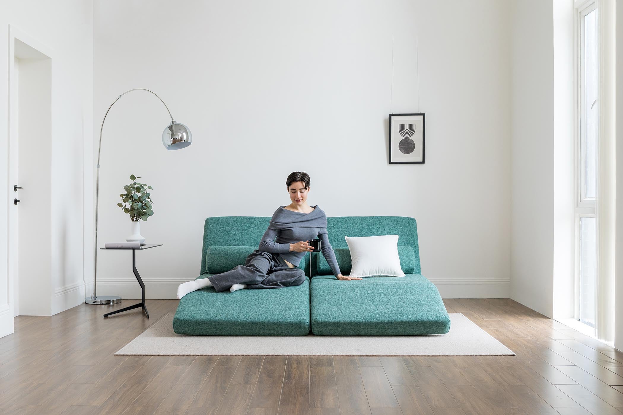 model sitting on sofa bed in lounge mode in living room scene
