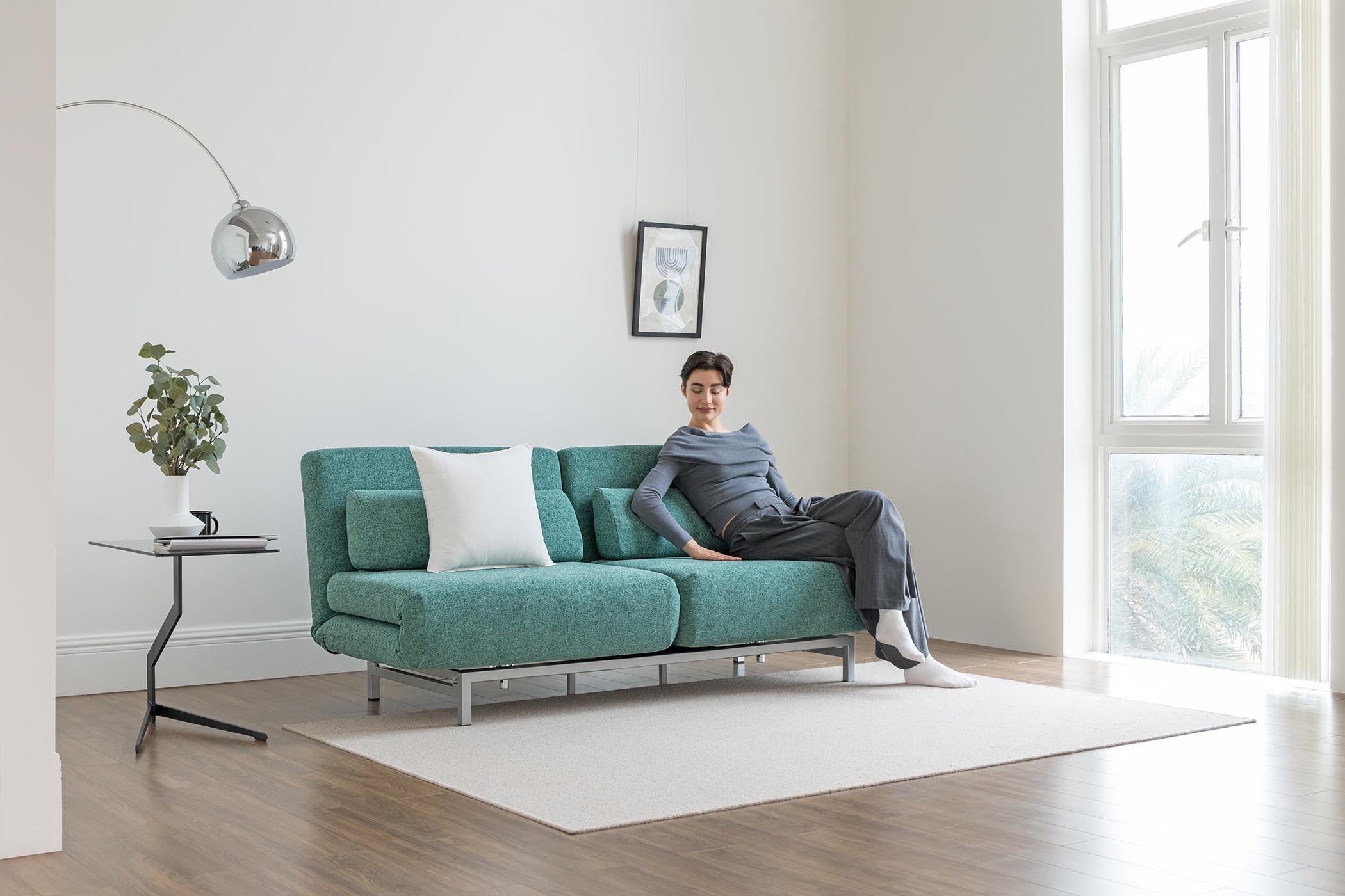 model sitting on sofa bed in living room scene