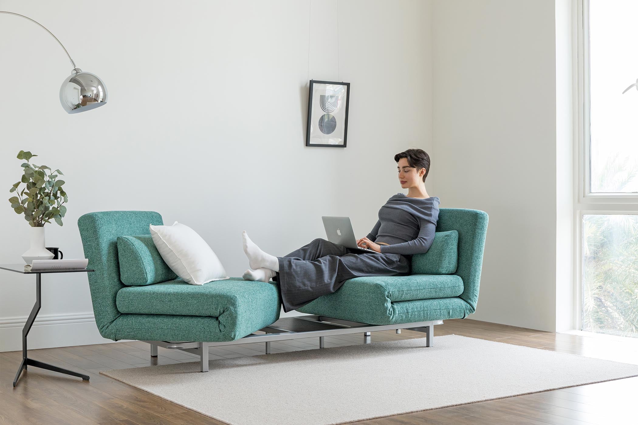 model sitting on the turning sofa bed in living room scene