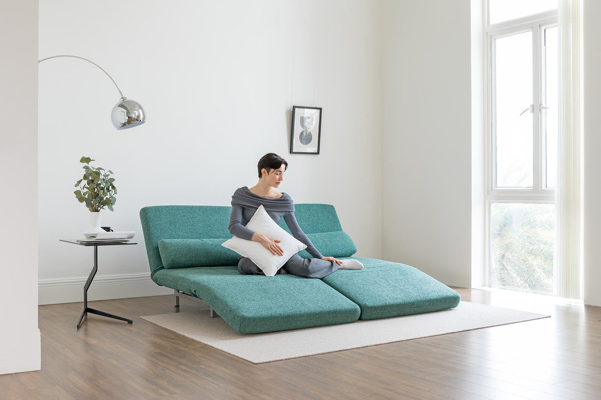 model sitting on sofa bed in lounge mode in living room scene