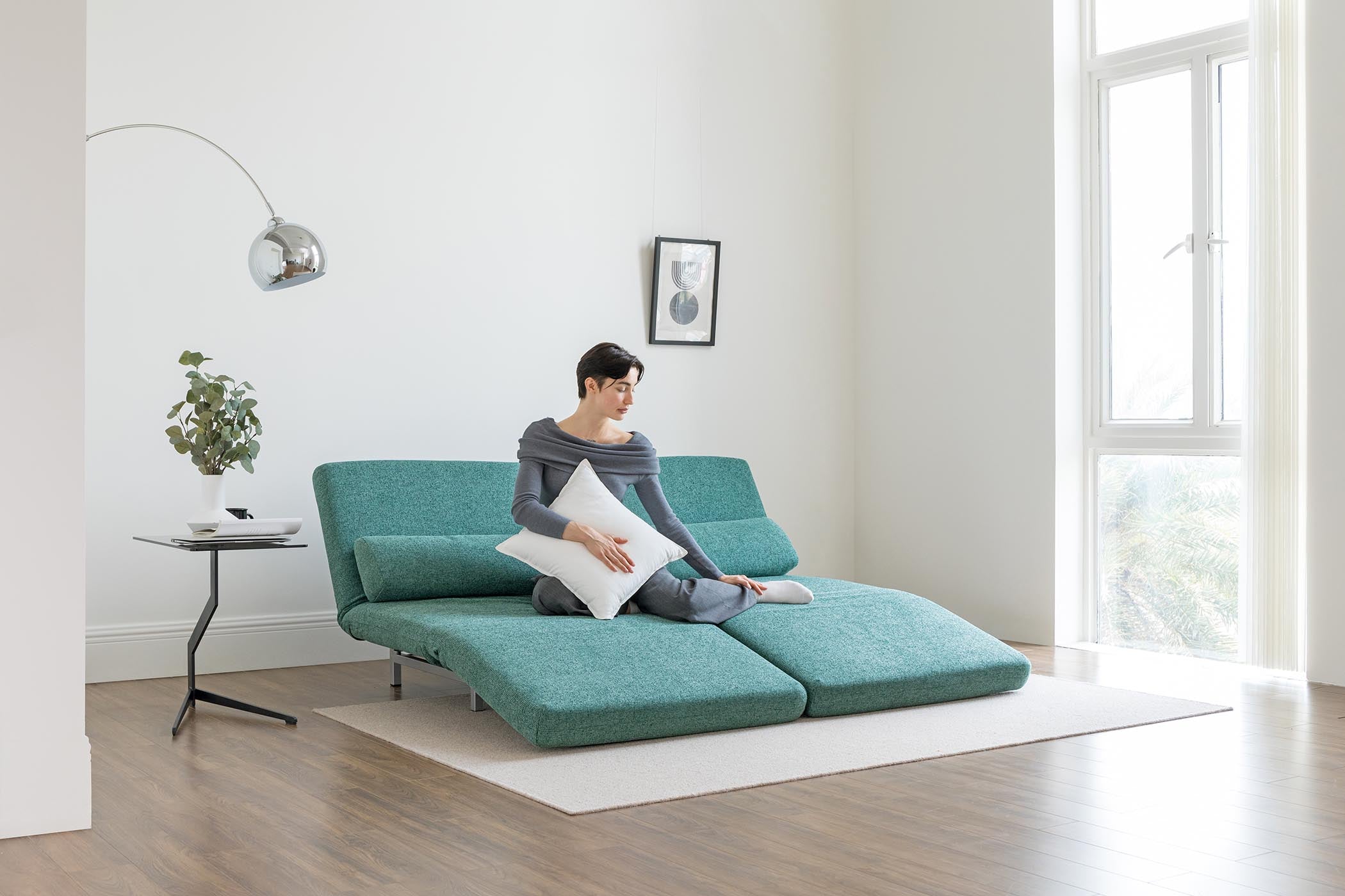 model sitting on sofa bed in lounge mode in living room scene