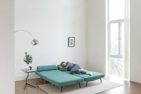 model sleeping on sofa bed in living room scene